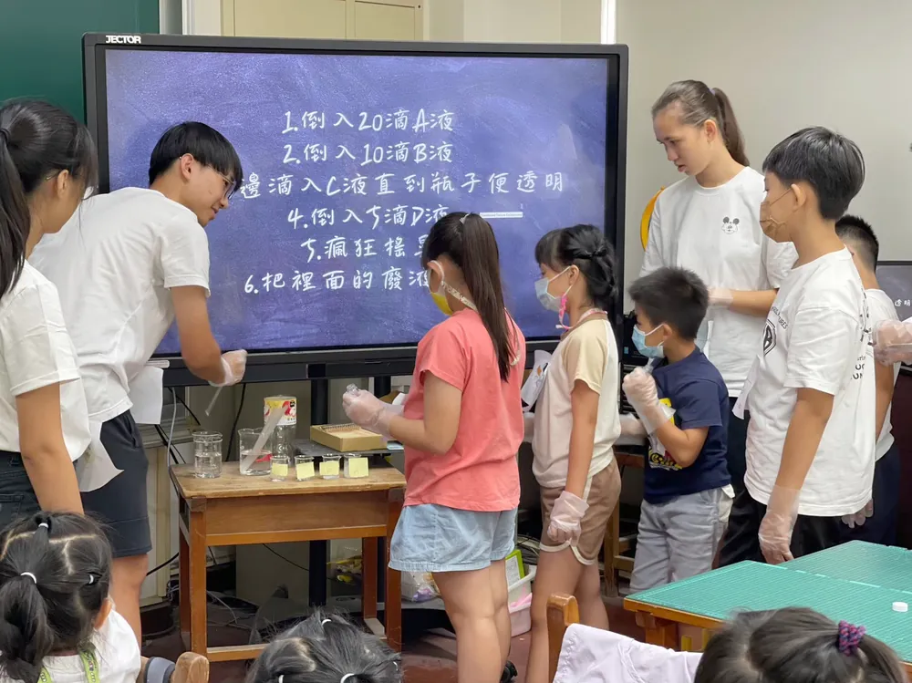 志工與孩子圍在投影幕前，照著步驟一滴一滴加入藥劑