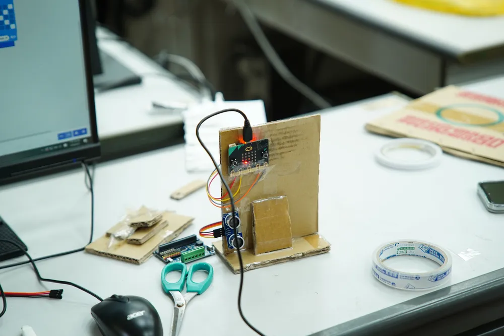 桌上的紙箱智慧家園，接上了 Microbit 電路板與感測器