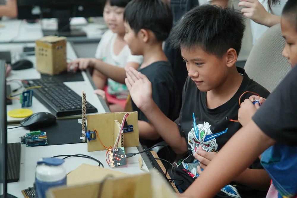 孩子們盯著螢幕，用 Microbit 控制自己用紙箱做的智慧家園