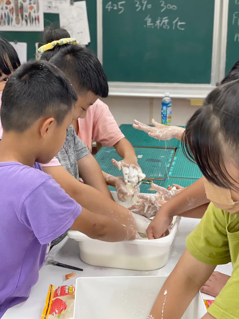 孩子們把手伸進白色盆子裡，感受又硬又軟的流體