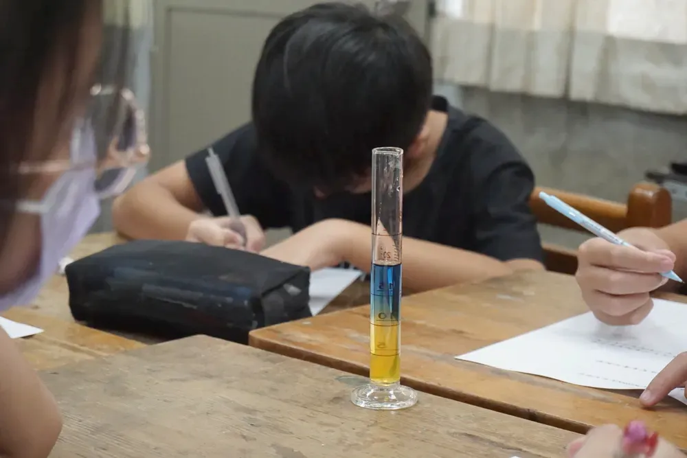 量筒裡，黃色與藍色的液體清楚分成上下兩層
