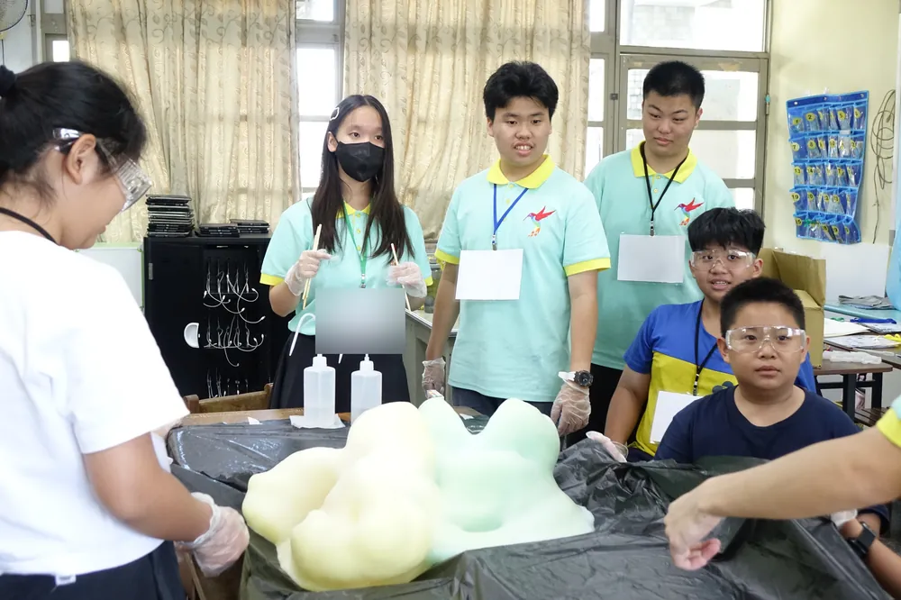 志工與孩子圍著黑色桌布，看大象牙膏的泡沫湧出