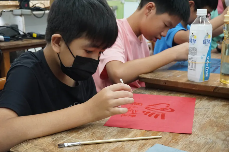 孩子專心地在紅紙上作畫